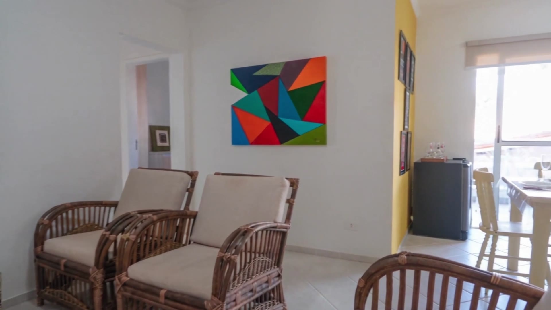 Sala de estar do Cantinho Ubatuba, com parede amarela e decoração descontraída
