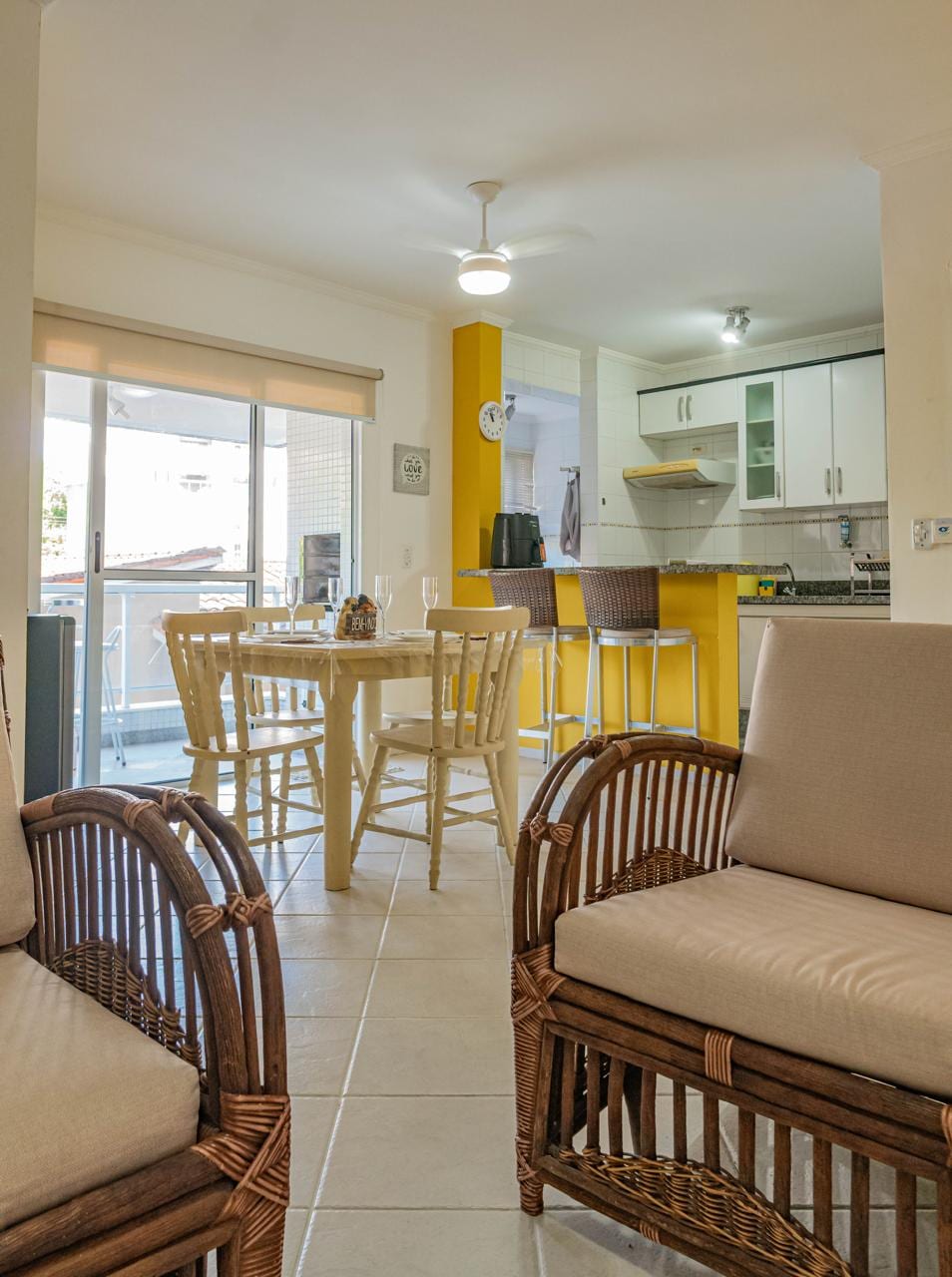 Sala integrada à cozinha americana, com parede amarela